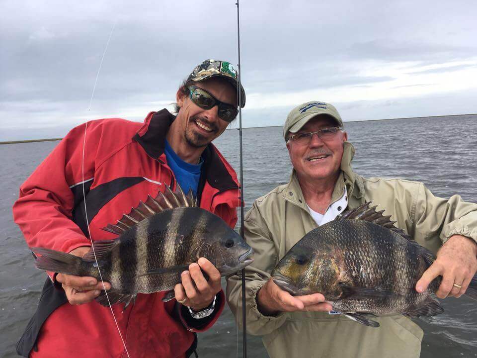 men smiling holding a big fish boat charter services 1
